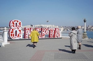 Женщин приглашают сфотографироваться на фоне пластиковых цветов